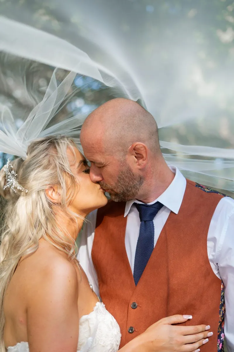 Bride and groom share a kiss beneath the veil